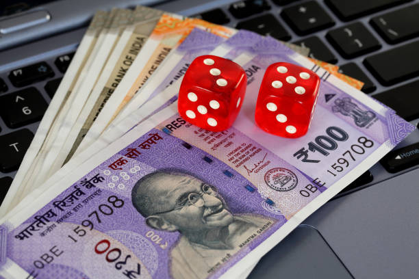 Red dice and Indian currency notes on laptop keyboard